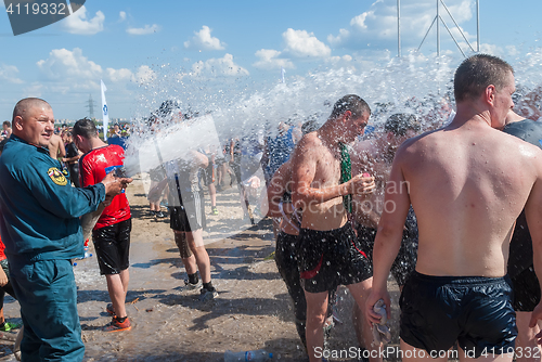 Image of Firefighter pours water athletes after finishing