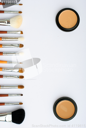 Image of makeup brush and cosmetics, on a white background