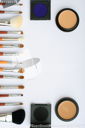 Image of makeup brush and cosmetics, on a white background