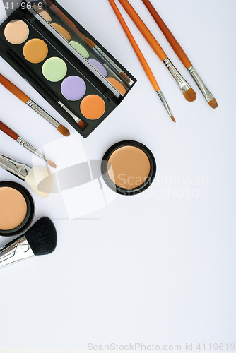 Image of makeup brush and cosmetics, on a white background