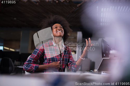 Image of woman at her workplace in startup business office listening musi