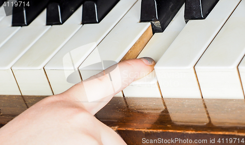 Image of Young unrecognizable girl child, playing piano by pressing down 