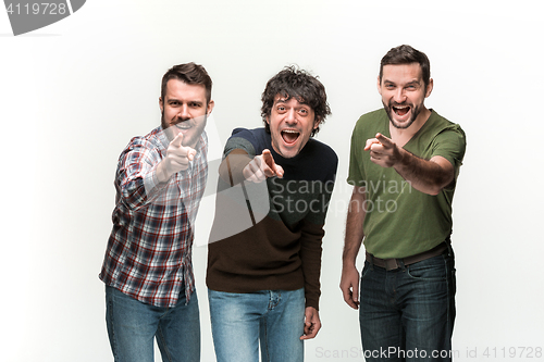 Image of The three men are smiling, looking and pointing at camera