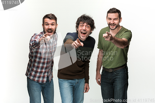 Image of The three men are smiling, looking and pointing at camera