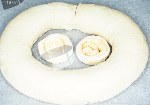 Image of Closeup of raw cinnamon roll and cinnamon buns on baking paper