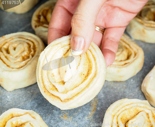 Image of Closeup of raw cinnamon roll and cinnamon buns on baking paper