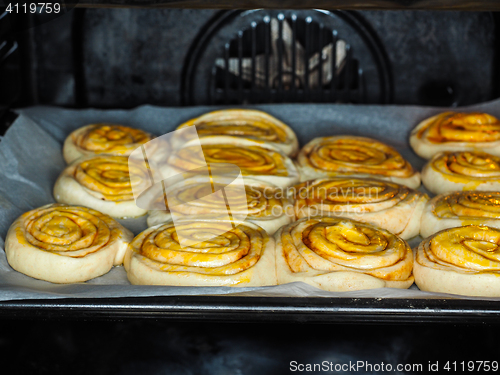 Image of Closeup of raw cinnamon buns after proofing with egg yolk, on ba