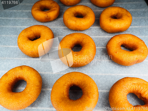 Image of Closeup of freshly made dark brown doughnuts on baking paper