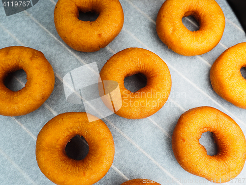 Image of Closeup of freshly made dark brown doughnuts on baking paper