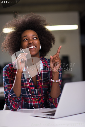 Image of black woman in modern office at her workplace speeking on phone 