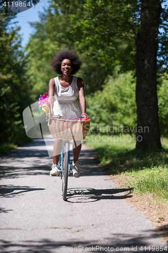 Image of pretty young african american woman riding a bike in forest