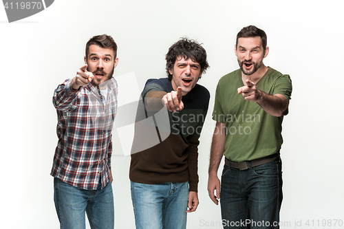 Image of The three men are smiling, looking and pointing at camera