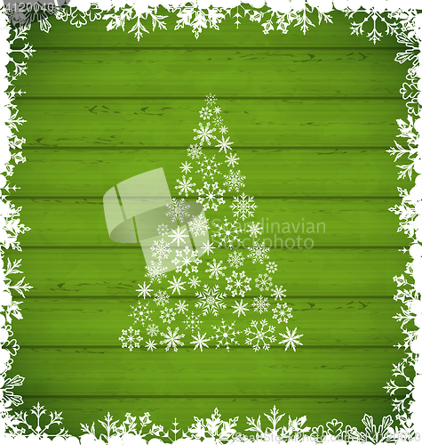 Image of  Christmas pine and border made of snowflakes on green wooden ba