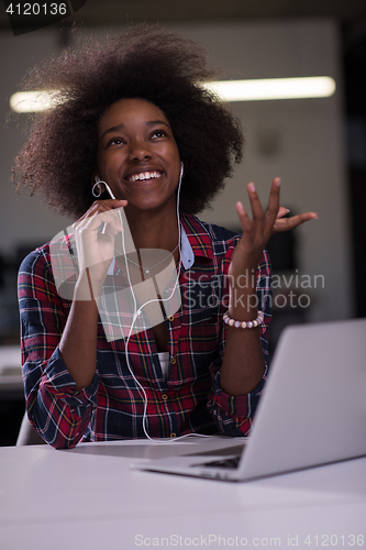 Image of black woman in modern office at her workplace speeking on phone 