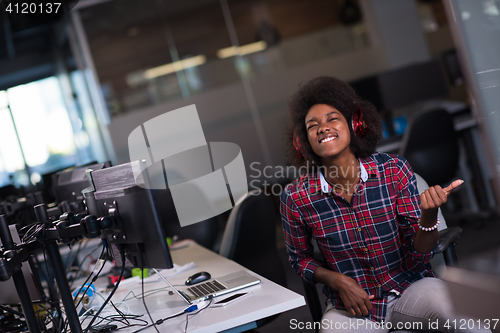 Image of woman at her workplace in startup business office listening musi