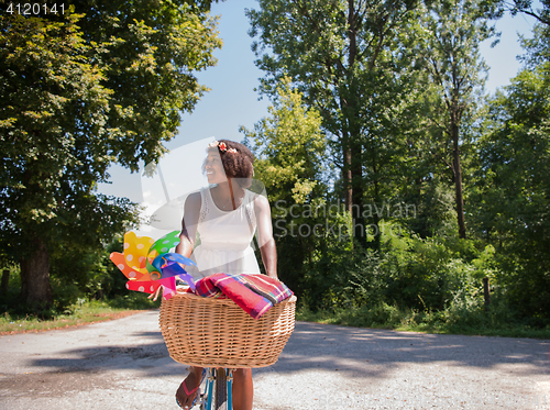 Image of pretty young african american woman riding a bike in forest