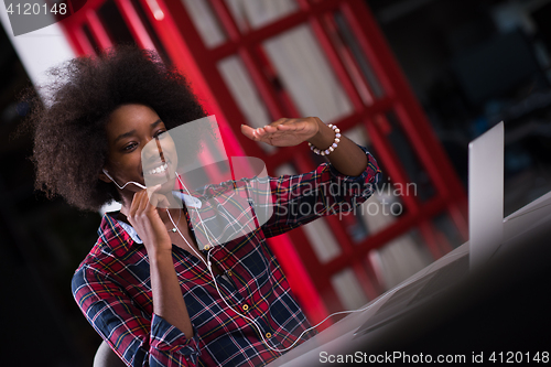 Image of black woman in modern office at her workplace speeking on phone 