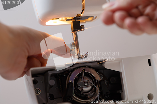 Image of Seamstress prepares sewing-machine to work