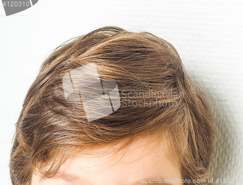 Image of Closeup of a neet hairstyle on a young boy, towards a white wall