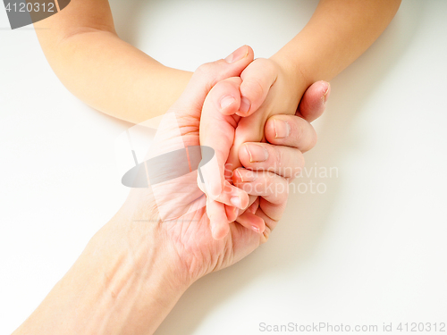 Image of Toddlers hands in fathers hand, towards, on a white table