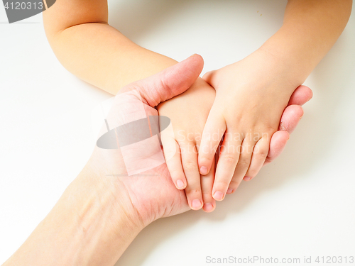 Image of Toddlers hands in fathers hand, towards, on a white table