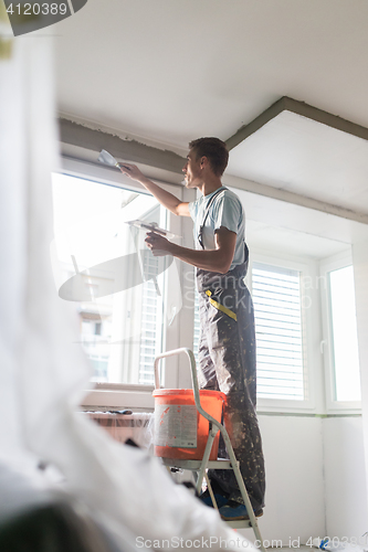 Image of Plasterer renovating indoor walls and ceilings. Construction finishing works.