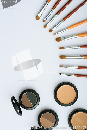 Image of makeup brush and cosmetics, on a white background