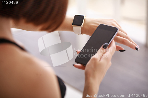 Image of using her smartwatch and phone at home in the living room