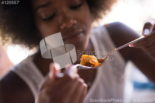 Image of a young African American woman eating pasta