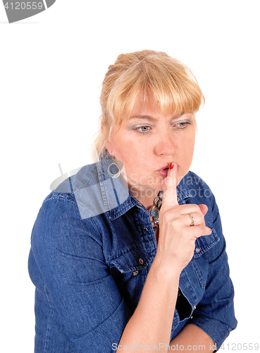 Image of Closeup of blond woman with finger over mouth.