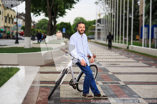 Image of young hipster man with fixed gear bike on city street