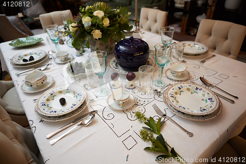 Image of Beautifully decorated table set with flowers, candles, plates and serviettes for wedding or another event in the restaurant.