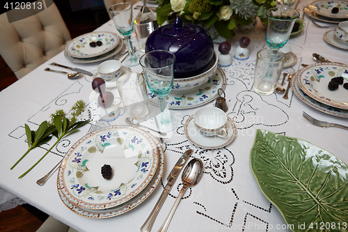 Image of Beautifully decorated table set with flowers, candles, plates and serviettes for wedding or another event in the restaurant.