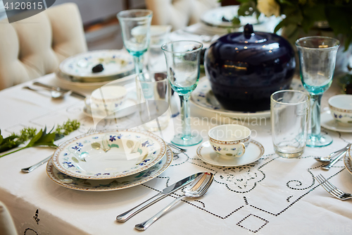 Image of Beautifully decorated table set with flowers, candles, plates and serviettes for wedding or another event in the restaurant.