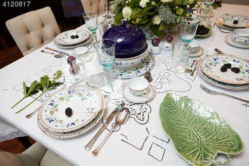 Image of Beautifully decorated table set with flowers, candles, plates and serviettes for wedding or another event in the restaurant.