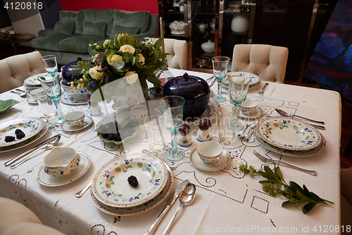 Image of Beautifully decorated table set with flowers, candles, plates and serviettes for wedding or another event in the restaurant.