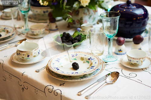 Image of Beautifully decorated table set with flowers, candles, plates and serviettes for wedding or another event in the restaurant.