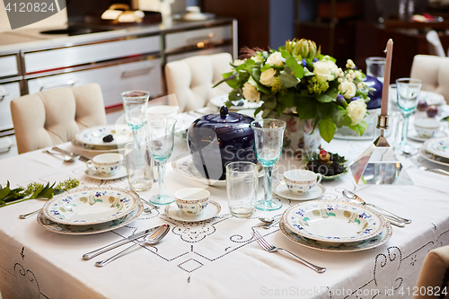 Image of Beautifully decorated table set with flowers, candles, plates and serviettes for wedding or another event in the restaurant.