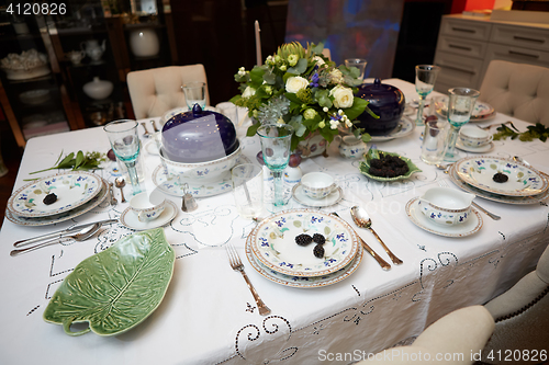 Image of Beautifully decorated table set with flowers, candles, plates and serviettes for wedding or another event in the restaurant.