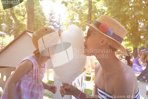 Image of Child eats cotton candy with mom in city street