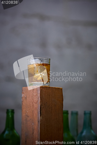 Image of Glass of whiskey with ice on old wooden bar