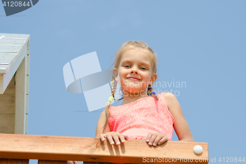 Image of Happy girl climbed on the playground and looked down smiling