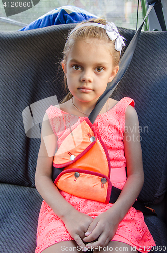 Image of A child of six sitting in the back seat of the car and strapped in using a restraint device