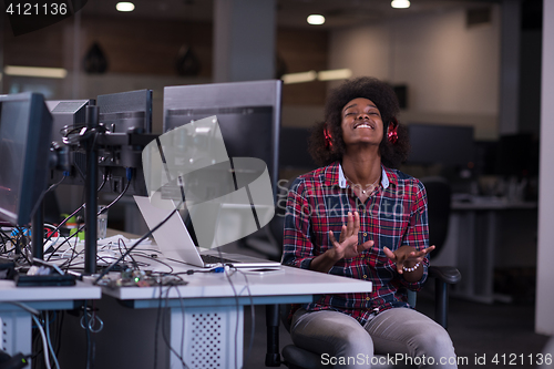 Image of woman at her workplace in startup business office listening musi