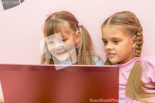 Image of Two girls looking at laptop and smiling