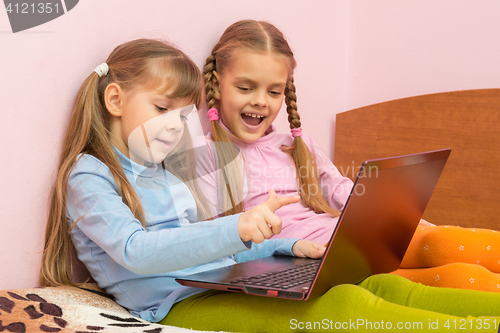 Image of Two girls include laptop at work, sitting on the bed