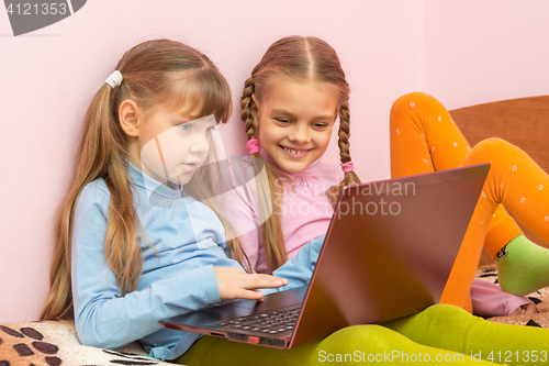 Image of Two girls play computer games on a laptop