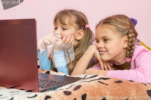 Image of Sisters lying on bed looking at laptop cartoon