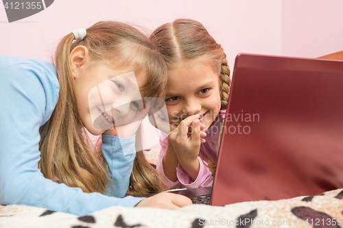 Image of Sisters watching a cartoon on a laptop and laughing at a funny moment