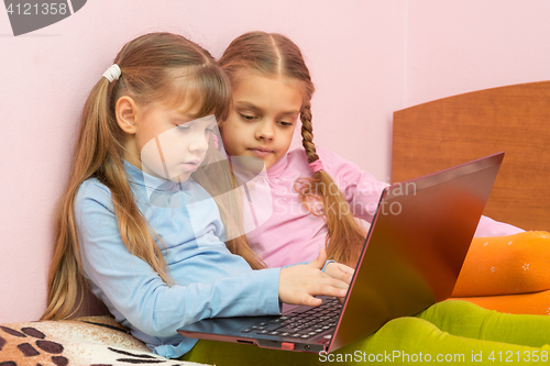 Image of Two girls pushing a search query on a laptop keyboard